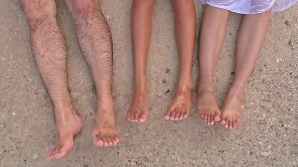 若い家族がビーチで楽しんで 足を打つ波とビーチに横たわる トップダウン ビュー スローモーションで撮影します — ストック動画