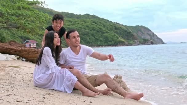 若い家族がビーチで楽しんで 両親を驚かせるために実行します 少年の白い男と若い中国の女性 スローモーションで撮影します 映画を見る — ストック動画