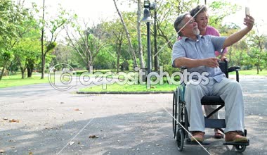 Parkta ve tekerlekli sandalyede kıdemli çift. Parkta Çinli eski çift, rahatlatıcı, gülümseyen. Karısıyla tekerlekli sandalyede adam. Boşluk Kopyala.