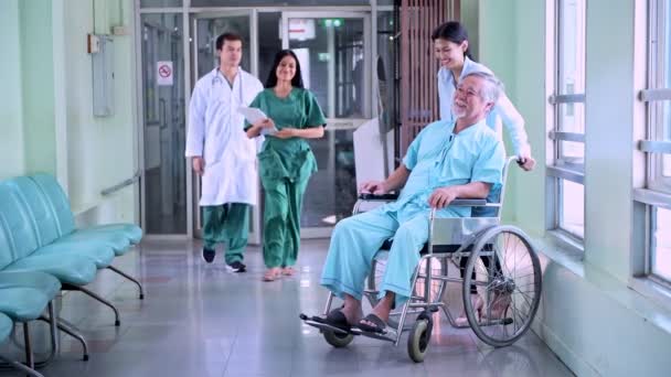 资深病人在轮椅与保险人 来自保险公司的美丽中国女人与老中国人在轮椅上谈医院走廊的保险政策 — 图库视频影像