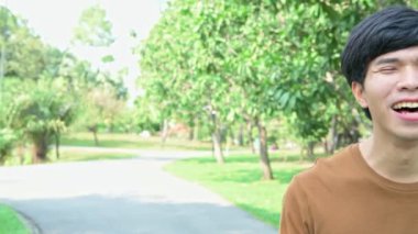 Parkta gülen Asyalı genç adam.