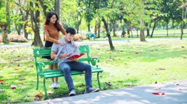 Parkta çift birlikte eğleniyoruz. Çinli çift tezgah üzerinde oturup birbirleri ile konuşuyor. Aşk ve ilişki konsepti.