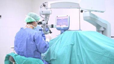 Göz cerrahı iş başında. Genç beyaz erkek cerrah ile üst düzey bir hastaya ameliyat onun güzel Çin Yardımcısı kadın. Gerçek ameliyathane oda. Tıp kavramı.