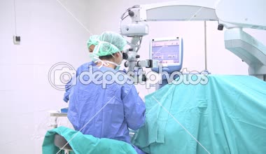 Göz cerrahı iş başında. Genç beyaz erkek cerrah ile üst düzey bir hastaya ameliyat onun güzel Çin Yardımcısı kadın. Gerçek ameliyathane oda. Tıp kavramı. 