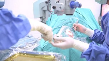 Göz cerrahı iş başında. Genç beyaz erkek cerrah ile üst düzey bir hastaya ameliyat onun güzel Çin Yardımcısı kadın. Gerçek ameliyathane oda. Tıp kavramı.