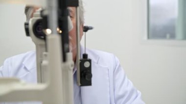 Gözlükçü iş başında. Üst düzey Çinli gözlükçü portre göz görme ölçüm makine işletim. Gerçek gözlükçü hastane odasında. Tıp kavramı.