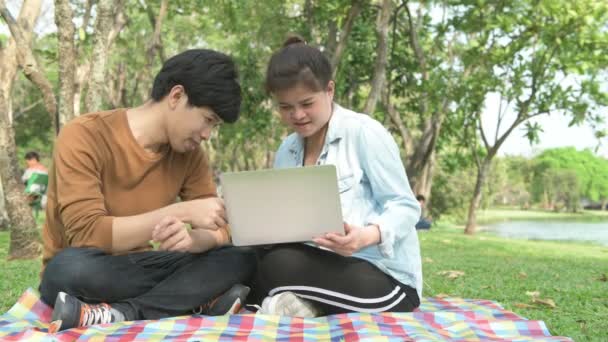 学生们在公园里学习 亚洲男人和女人坐在一起在公园里 用笔记本电脑在一起聊天 教育理念 — 图库视频影像