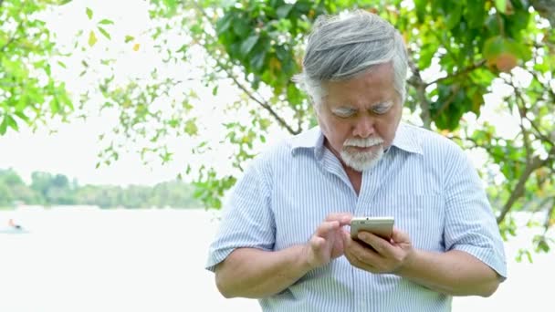 Старший Чоловік Тиражує Щоб Використовувати Свій Телефон Парку Старий Азіатський — стокове відео