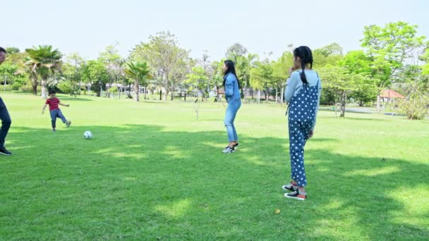 午後に公園でサッカーをしている家族 若い男の子 公園で一緒にサッカーをしている女の子とドイツの白人男性とアジアの女性 ウィークエンドファミリーファンコンセプト — ストック動画