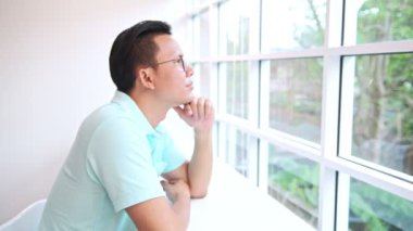 Pencere arka plan karşı karşıya sandalyede oturan adam. Mavi gömlekli ağaç arka planda dönük beyaz sandalye üzerinde oturan genç Çinli erkek. Akıllı co ofis alanı kavramı çalışma,.