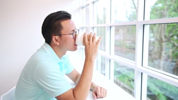 Man Sitter Stol Inför Fönsterbakgrund Unga Kinesiska Män Blå Skjorta — Stockvideo