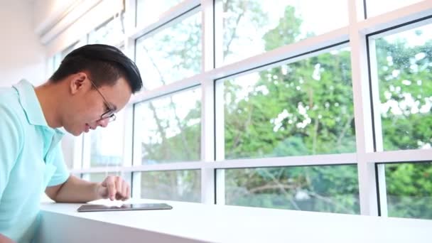 自信的商人坐在办公室里用平板电脑 年轻的中国男性穿着蓝色衬衣坐在椅子上看着自信 聪明的合作 小企业所有者 办公室空间概念 — 图库视频影像