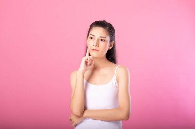 Beyaz tanktop kıyafeti süre ayakta ve pembe arka plan üzerinde izole kamera gülümseyen düşünme poz ile gülümseyen bir çekici kadın portresi.
