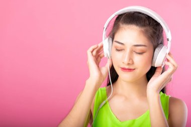 Dinleme ve pembe arka plan izole onun kulaklık ile müzik dans yaz kıyafeti mutlu bir çekici kadın portresi.