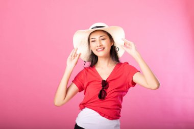 Yaz kıyafeti ve süre ayakta ve pembe arka plan üzerinde izole kamera bakarak poz şapka gülümseyen bir çekici kadın portresi.