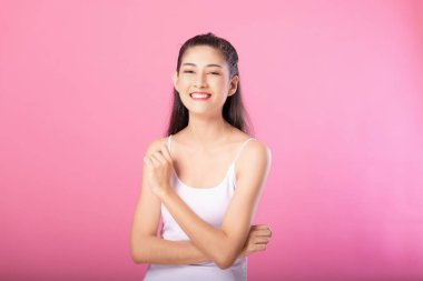 Beyaz tanktop kıyafeti süre ayakta ve pembe arka plan üzerinde izole kamera gülümseyerek poz gülümseyen bir çekici kadın portresi.