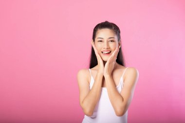 Beyaz tanktop kıyafeti süre ayakta ve pembe arka plan üzerinde izole kamera gülümseyen sürpriz poz ile gülümseyen bir çekici kadın portresi.