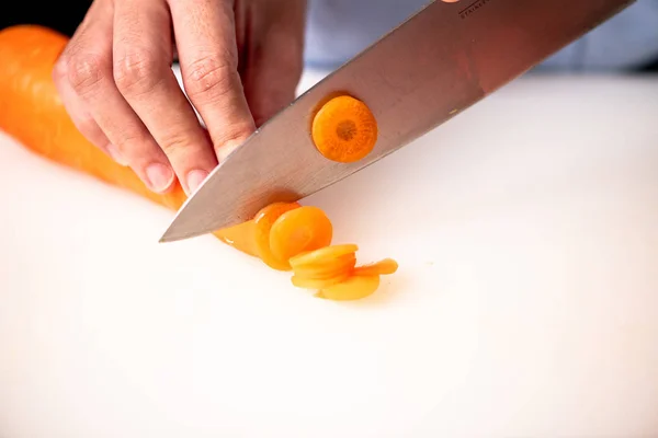 Woman chopping carrots in kitchen. — Stock Photo, Image