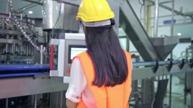 Kadın mühendis fabrika içinde işte. Büyük fabrikasında çalışan güzel genç Çinli mühendis. Kask ve ceket ile. Arka planda yüksek teknoloji otomatik makine. 