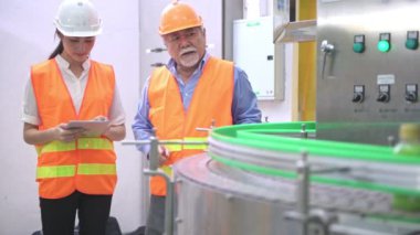 Senior kalite müfettişi fabrika genç takım üyesi öğretim. Çin eski erkek genç ekibiyle şişe üretim hattında arka plan ile kalite sorunu tartışıyor.