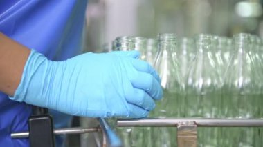 Cam şişe dolum Makinası fabrikasında. Fabrika üretim hattında bir konveyör bant şişelerde satır. Fabrika işçisi üzerinde çalışıyor. Doğal ışık ile gerçek fabrika çekilmiş.