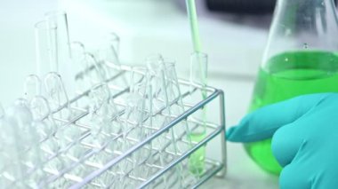 Bilim adamı giyen şişesi test tüpünden içine koyarak kimyasal sıvı eldiven. Atış kapatın. Bilim kavramı.