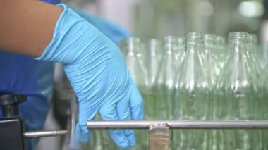 Cam şişe dolum Makinası fabrikasında. Fabrika üretim hattında bir konveyör bant şişelerde satır. Fabrika işçisi üzerinde çalışıyor. Doğal ışık ile gerçek fabrika çekilmiş.