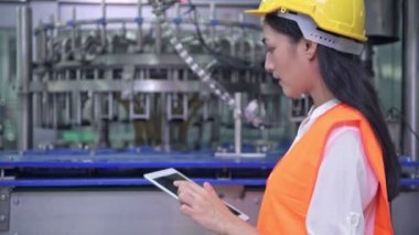 Kadın mühendis fabrika içinde işte. Büyük fabrikasında çalışan güzel genç Çinli mühendis. Kask ve ceket ile. Arka planda yüksek teknoloji otomatik makine.