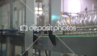 Cam şişe dolum Makinası fabrikasında. Fabrika üretim hattında bir konveyör bant şişelerde satır. Fabrika işçisi üzerinde çalışıyor. Doğal ışık ile gerçek fabrika çekilmiş.