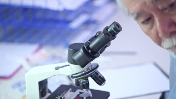 顕微鏡に探していた上級研究科学者にクローズ アップ シニア男性と顕微鏡を探してアジアの女性 — ストック動画