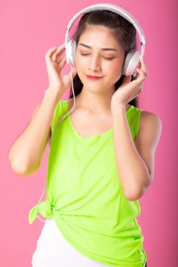 Dinleme ve pembe arka plan izole onun kulaklık ile müzik dans yaz kıyafeti mutlu bir çekici kadın portresi.