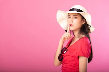 Yaz kıyafeti ve süre ayakta ve pembe arka plan üzerinde izole kamera bakarak gizli hush poz şapka çekici kadın portresi.