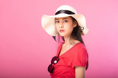 Yaz kıyafeti ve süre ayakta ve pembe arka plan üzerinde izole kamera bakarak poz şapka gülümseyen bir çekici kadın portresi.