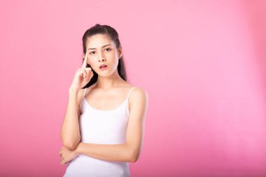 Beyaz tanktop kıyafeti süre ayakta ve pembe arka plan üzerinde izole kamera gülümseyen düşünme poz ile gülümseyen bir çekici kadın portresi.