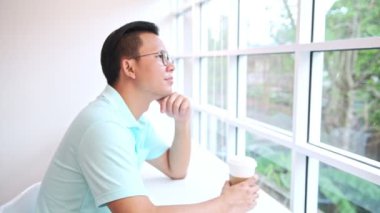 Pencere arka plan karşı karşıya sandalyede oturan adam. Mavi gömlekli ağaç arka planda dönük beyaz sandalye üzerinde oturan genç Çinli erkek. Akıllı co ofis alanı kavramı çalışma,.