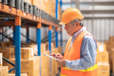 Kıdemli ambar operatör portre. Emanet şapkalı yaşlı Çinli adam poz tablet ile şişe ambarı arka planda tutan gülümseme.