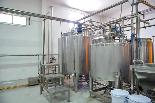 Beverage production line background. A liquid mixer tank pumping beverage mix into bottle filling machine. Beverage manufacturing concept.