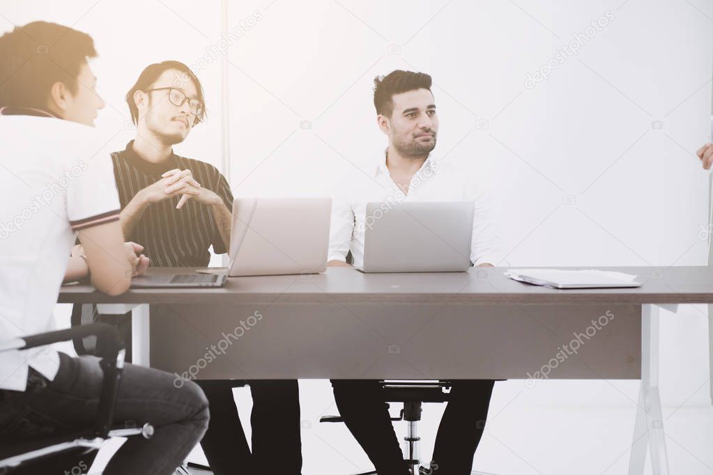 Businessman brainstorming together. Indian male looking happy with his asian team during brain storm session. Muted tone effect.