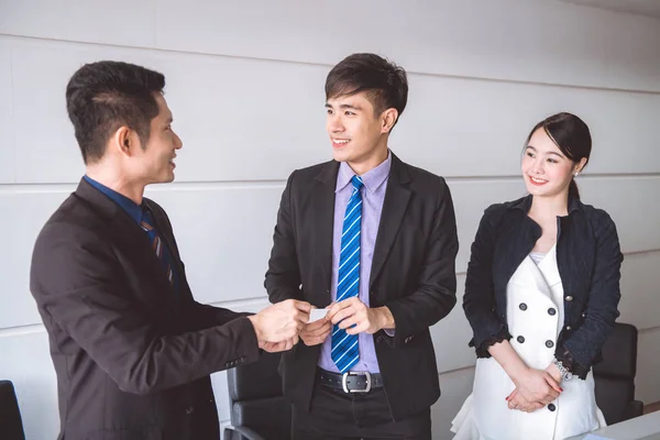 Young businessman giving name card to his customer. Asian man in suit with his beautiful woman giving name card to a businessman as self introduction.
