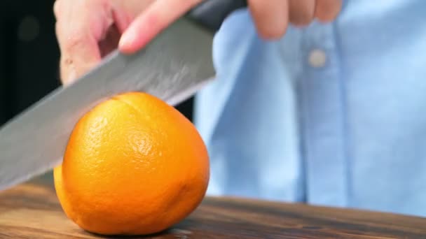 Frau Schneidet Ganze Orange Mit Messer Auf Holzbrett — Stockvideo