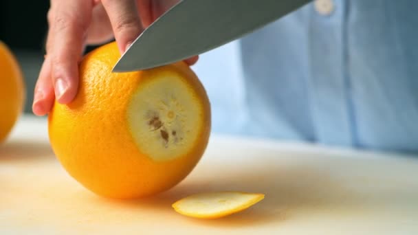 Frau Schneidet Orange Mit Messer Auf Schneidebrett — Stockvideo