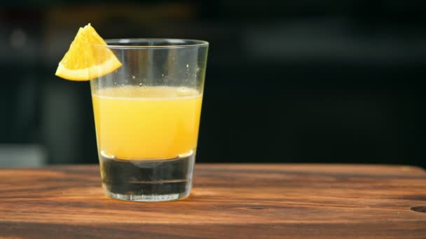 木製のテーブルから新鮮なオレンジ ジュースのガラスを取る女性 — ストック動画