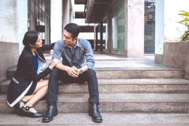 Sokakta oturan işsiz adam. Asya adam stres bakarak ve duygusal ve arkadaşı gelip ona yardım. Ofis Binası arka plan.