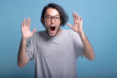 Genç adam heyecan şok edici poz mavi renkli sakallı. Çok heyecanlı Asya genç hipster ağız açık Vay poz, yarım vücut vurdu. Genç nesil yenilikçi kavram.