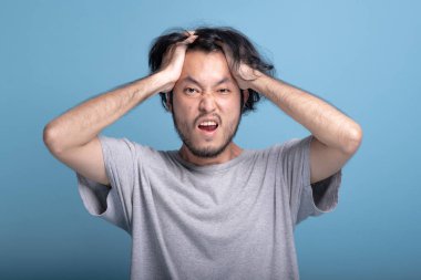 Genç adam heyecan şok edici poz mavi renkli sakallı. Çok Asya genç hippi saç, ifade, yarım vücut vurdu şok edici dokunmadan eller ile sürpriz. Genç nesil yenilikçi kavram.