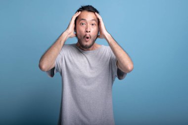 Genç adam heyecan şok edici poz mavi renkli sakallı. Son derece sürpriz Asya genç hippi kafa dokunuyor, ifade, yarım vücut vurdu şok edici elleri olan. Genç nesil yenilikçi kavram.