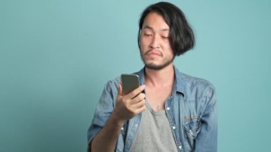 odaklı smartphone kullanarak, cebinden para alarak ve gadget'ı koyarak Genç Asyalı adam