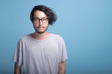 Genç adam portre mavi arka planda sakallı. Asya genç hippi gülümseyen, yarım vücut vurdu. Genç nesil yenilikçi kavram.