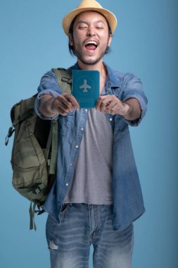 Genç adam gezgin mavi arka planda backpacking sakallı. Pasaport, yarım vücut vurdu tutarak kendine güvenen Asya genç hippi. Genç nesil yenilikçi tatil seyahat kavramı.