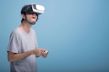 Genç adam Vr oyunu mavi arka planda çalmaya sakallı. VR kulaklık, yarım vücut vurdu giyen çok üzgün Asya genç hippi. Genç nesil yenilikçi gevşeme kavramı.
